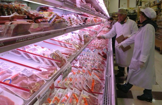 图文:纽约一家超市的员工在猪肉冷藏柜前检查